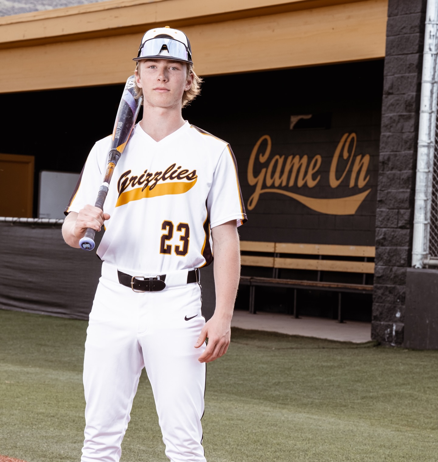 London Wooten in his Galena number 23 baseball uniform, holding his bat outside the dugout